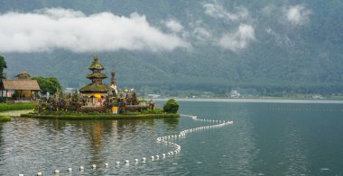 Bali 'deki Beratan Gölü' nün doğal manzarası. Doğal gölü çevreleyen yeşil tepeler ve temiz su, ve sabah gökyüzü bulutsuz. Gölün ortasında bir Hindu tapınağı var.