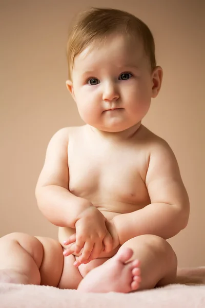 Babymeisje zit in bed — Stockfoto