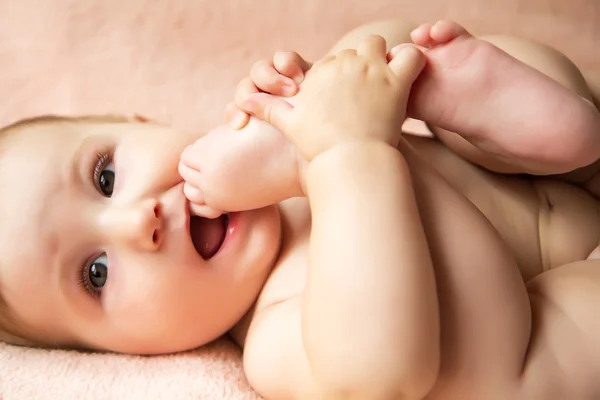 Baby girl playing with her legs — Stock Photo, Image