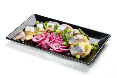 Hafif tuzlanmış ringa balığı, haşlanmış patates ve soğanlı aperatif. Beyaz bir arkaplanda izole edilmiş