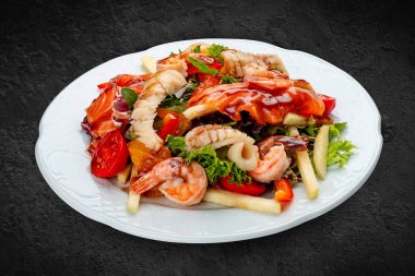 Karides, somon ve kalamar, portakal ve tatlı biberli salata. Siyah bir arkaplanda izole edilmiş