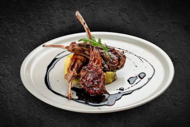 Kuskus ve vişne soslu kuzu pirzolası. Siyah bir arkaplanda izole edilmiş