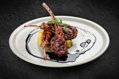 Kuskus ve vişne soslu kuzu pirzolası. Siyah bir arkaplanda izole edilmiş