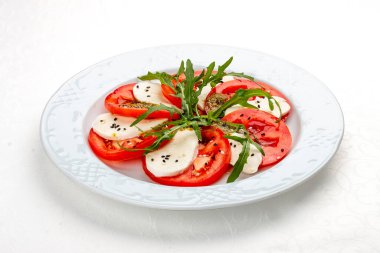 Mozzarella, domates ve pesto soslu Caprese salatası. Geleneksel bir İtalyan yemeği. Beyaz bir arkaplanda izole edilmiş.
