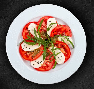 Mozzarella, domates ve pesto soslu Caprese salatası. Geleneksel bir İtalyan yemeği. Siyah bir arkaplanda izole edilmiş.