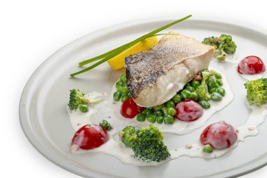 Sebze yastığına tünemiş levrek. Beyaz bir arkaplanda izole edilmiş.