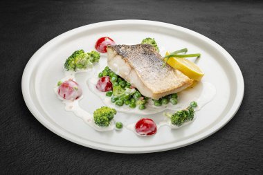 Sebze yastığına tünemiş levrek. Siyah bir arkaplanda izole edilmiş.