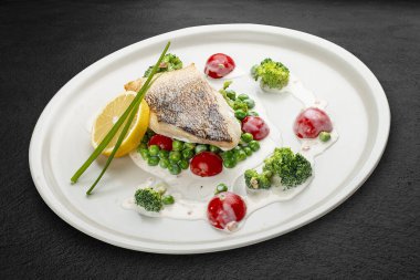 Sebze yastığına tünemiş levrek. Siyah bir arkaplanda izole edilmiş.