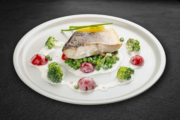 Sebze yastığına tünemiş levrek. Siyah bir arkaplanda izole edilmiş.