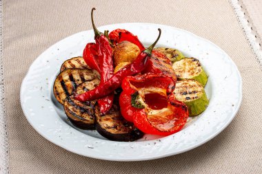 Beyaz bir tabakta ızgara sebze. Tatlı biber, domates, kabak, patlıcan..
