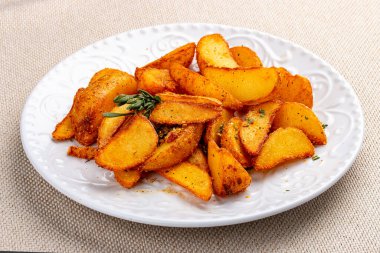 Dilimlenmiş patates, baharatlı Creole usulü. Beyaz bir tabakta.
