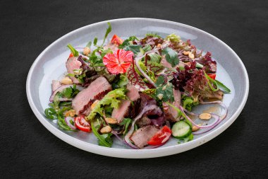 Soslu Josper-fırın dana salatası. Karanlık bir arka planda, izole. 