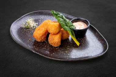 Baharatlı soslu gevrek ekmeğin içinde kızarmış mozzarella peyniri. Karanlık bir arka planda, izole. 