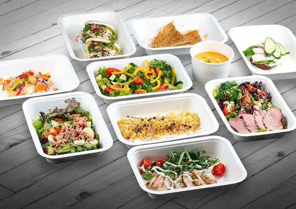 A set of healthy food dishes in ecological packaging on a wooden background. Food delivery. Takeaway.