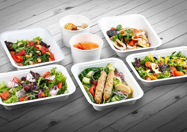 A set of healthy food dishes in ecological packaging on a wooden background. Food delivery. Takeaway.