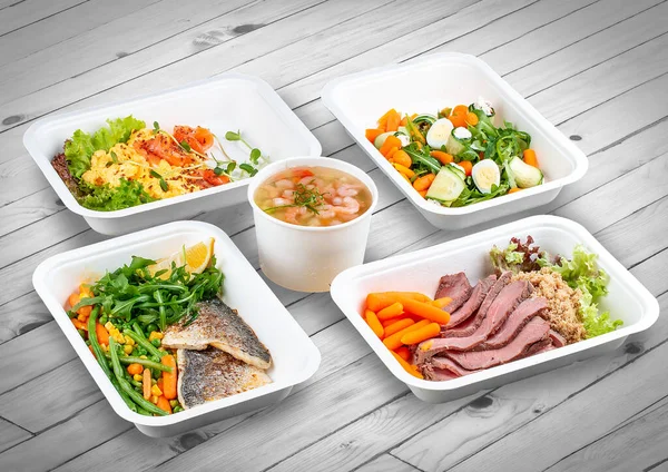 A set of healthy food dishes in ecological packaging on a wooden background. Food delivery. Takeaway.