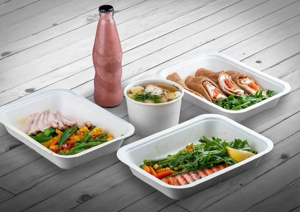 A set of healthy food dishes in ecological packaging on a wooden background. Food delivery. Takeaway.