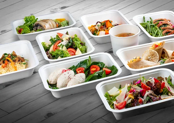 A set of healthy food dishes in ecological packaging on a wooden background. Food delivery. Takeaway.