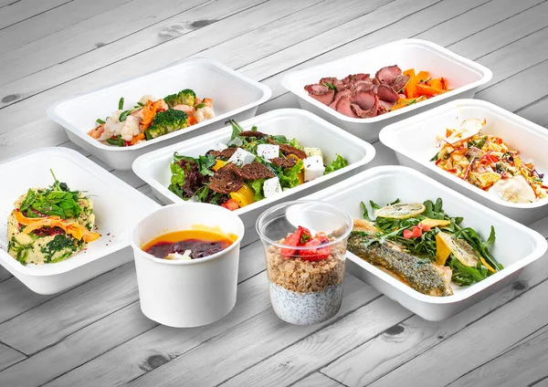 A set of healthy food dishes in ecological packaging on a wooden background. Food delivery. Takeaway.