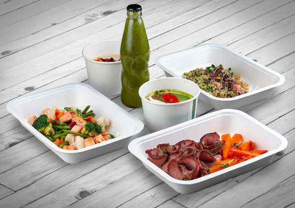 A set of healthy food dishes in ecological packaging on a wooden background. Food delivery. Takeaway.