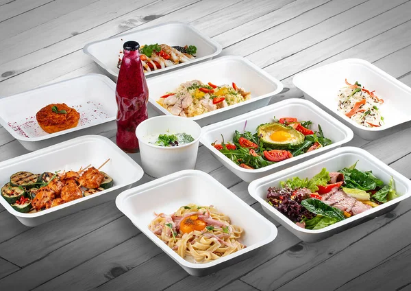 A set of healthy food dishes in ecological packaging on a wooden background. Food delivery. Takeaway.