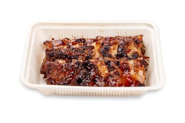 Izgara domuz pirzolası. Plastik bir kapta. Paket yemek. Hafif bir arkaplanda.