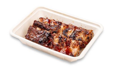 Izgara domuz pirzolası. Plastik bir kapta. Paket yemek. Hafif bir arkaplanda.