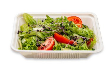 Taze sebzeli salata ve mikroyeşillik. Plastik bir kapta. Paket yemek. Hafif bir arkaplanda.