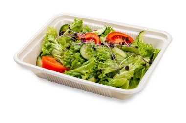 Taze sebzeli salata ve mikroyeşillik. Plastik bir kapta. Paket yemek. Hafif bir arkaplanda.