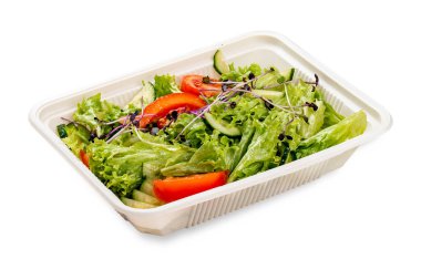 Taze sebzeli salata ve mikroyeşillik. Plastik bir kapta. Paket yemek. Hafif bir arkaplanda.