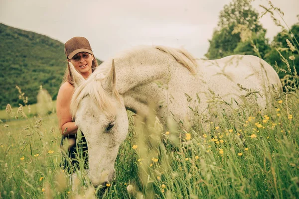Kobieta Łące Wysoką Trawą Pieszcząca Białego Konia — Zdjęcie stockowe