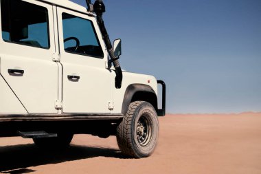 Güneşli bir günde Namib Çölü 'nün kırmızı kumlarında beyaz bir araba duruyor. Sossusvlei, Namibya