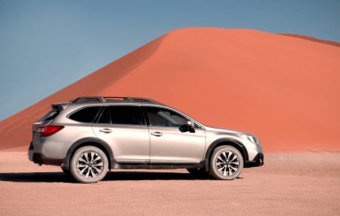 Subaru Outback, Namib Çölü 'nün ortasında Sossusvlei' nin kırmızı kum tepeciğinin yanında duruyor.. 