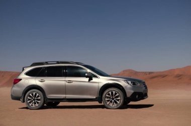 Güneşli bir günde Namib Çölü 'nün altın kumlarında gri bir araba duruyor.. 