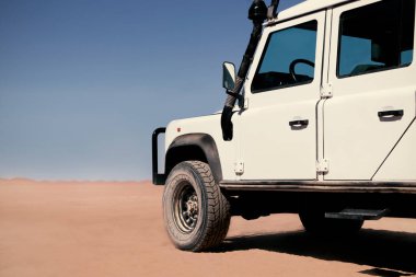 Güneşli bir günde Namib Çölü 'nün kırmızı kumlarında beyaz bir araba duruyor. Sossusvlei, Namibya