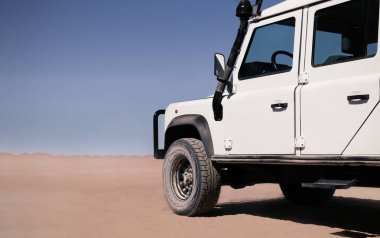 Güneşli bir günde Namib Çölü 'nün kırmızı kumlarında beyaz bir araba duruyor. Sossusvlei, Namibya