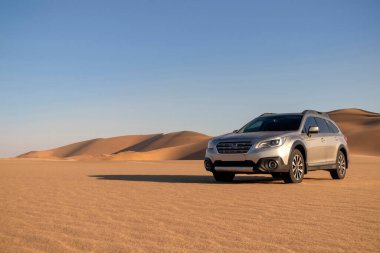 Gray Subaru in the sand of the Namib desert at a bright sky. Walvis Bay, Namibia.