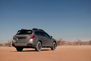 Gri Subaru, Namib çölünün kumlarında, parlak bir gökyüzünde. Walvis Körfezi, Namibya.