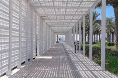 Ünlü Louvre Sanat Müzesi 'ne giden beyaz çarşaf geçidine dair fütüristik bakış açısı azalıyor. Ana girişi ışık ve gölgeli modern bir portal. Abu Dabi, BAE, Mart 2021