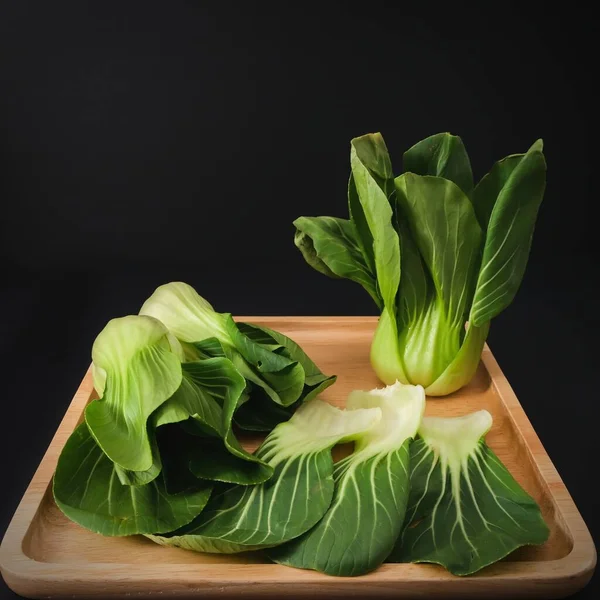 Baby Bok Choy vert biologique ou Brassica rapa chinensis sur plaque de bois sur fond noir. Légumes chinois populaires pour la cuisine asiatique.Une alimentation végétarienne et végétalienne saine. — Photo