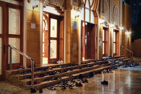 Los musulmanes se quitan los zapatos en los escalones de la entrada de la mezquita antes de las oraciones del viernes por la noche. Calzado exterior mezquita — Foto de Stock