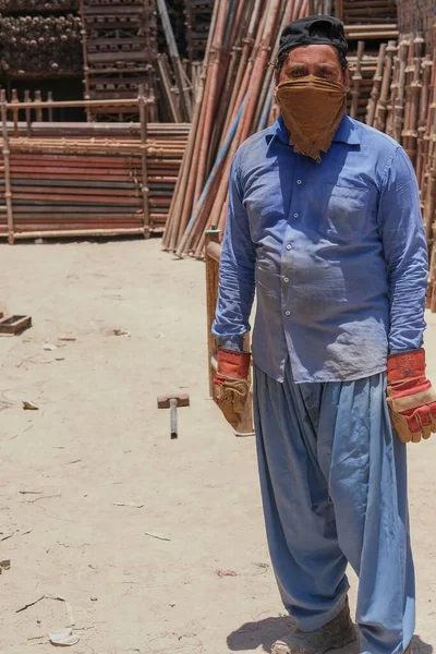 Ώριμος μετανάστης εργάτης της Μέσης Ανατολής που φοράει μουσουλμανική ανδρική μαντίλα, εργάζεται σε αποθήκη απορριμμάτων μετάλλων για ανακύκλωση και ποζάρει για φωτογραφία. Αμπού Ντάμπι, Ηνωμένα Αραβικά Εμιράτα, Ιούνιος 2021 — Φωτογραφία Αρχείου