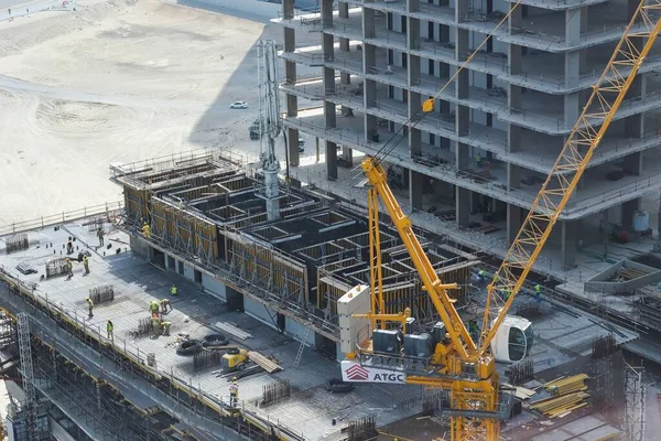 Vista superior para o canteiro de obras com grupo de construtores no telhado. Construção de arranha-céus moderno, projeto residencial de arranha-céus em Abu Dhabi, Emirados Árabes Unidos, março de 2022 — Fotografia de Stock