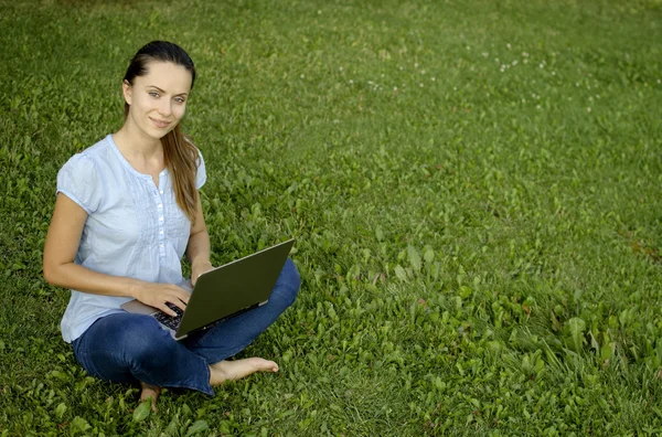 Young woman with laptop on green grass — Stock Photo, Image