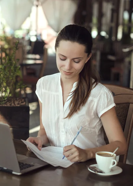 一个有吸引力的年轻商业女人坐在咖啡馆与 noteb — 图库照片