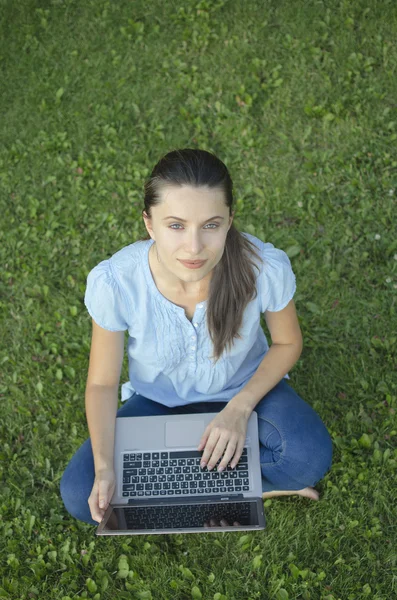 Young woman with laptop on green grass — Stock Photo, Image