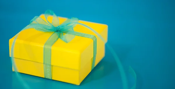 Желтая подарочная коробка на синем фоне — стоковое фото