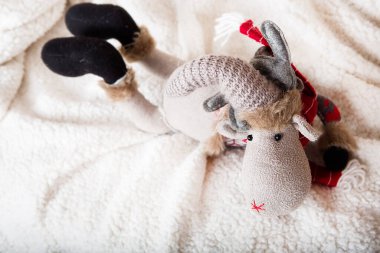 Noel örgü oyuncak geyiği koyun derisinin üzerinde yatıyor. Üst görünüm.