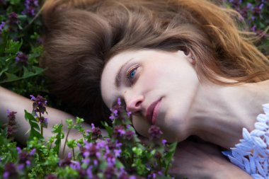 Genç ve rahat kadın kır çiçekleri arasında dinlenmenin tadını çıkarıyor. Üst görünüm.