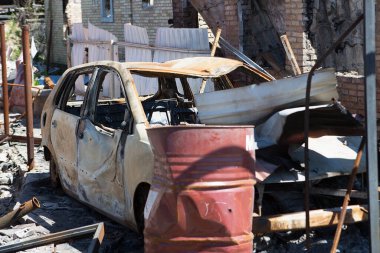 Bucha, Kyiv bölgesi - 5 Mayıs 2022: Şehrin bombalanmasından sonra yanan araba yıkılmış bir evin avlusunda duruyor. Rusya ile Ukrayna arasındaki savaş, 5 Mayıs 2022.
